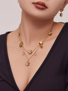 Dettaglio della collana a strati con ciondoli a fiore e cuore e pietre di zircone 5A dorate