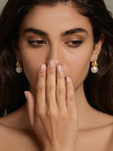 Boucles d'oreilles écureuil dorées avec perles blanches portées par un mannequin femme