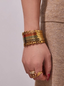Detail of stacked gold bangles with checkerboard enamel and geometric diamond accents