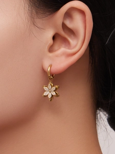 Dettaglio di orecchini a fiore dorati con cristalli di zirconia 5A indossati da una modella