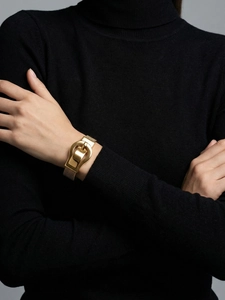 Close-up of gold mesh watch-band bracelet with horseshoe buckle on black knit sleeve