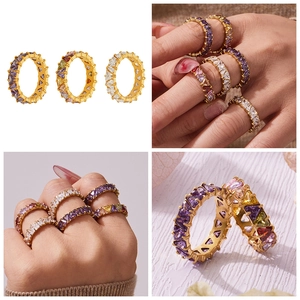 Dettaglio di anelli eternity dorati con zirconi cubici a cuore viola e bianchi