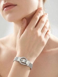 Close-up of silver mesh bracelet with buckle design on wrist, industrial luxury style