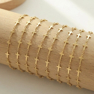 Polished gold geometric cross link bracelet wrapped on a wooden stand for women
