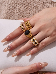 Close-up of four-piece gold ring set featuring black and white enamel and retro textures