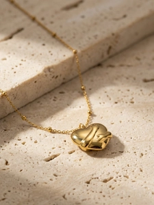 Macro shot of gold-plated embrace heart pendant on beaded stainless steel chain