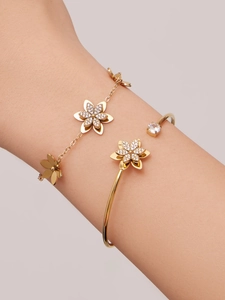 Dettaglio del set di gioielli a fiore dorato con zirconi brillanti su bracciale e rigido
