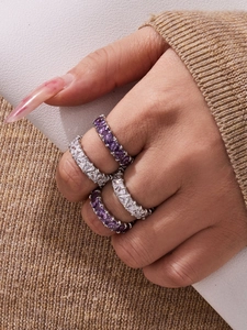 Dettaglio di anelli d'argento sovrapposti con zirconi viola e bianchi a taglio triangolo