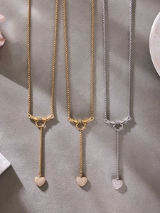 Détail macro de pendentifs cœur en zircone et collier avec fermoir en forme de mains