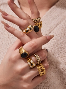 Close-up of gold stainless steel rings with checkered enamel and black oval gemstones