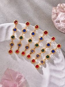 Details von bunten Zirkonia-Ohrringen auf einem weißen Tablett mit Blumendekor