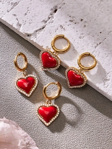 Gros plan détaillé des boucles d'oreilles cœur dorées avec émail rouge et zircon blanc
