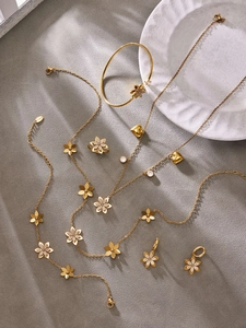 Dettaglio del set gioielli a fiori dorati con petali in zircone su sfondo in pietra