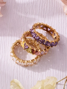 Dettaglio ravvicinato di tre anelli eternity con zirconi triangolari placcati oro 18 carati
