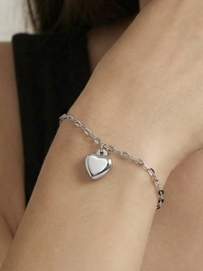 Close-up of polished stainless steel heart pendant bracelet on woman's wrist