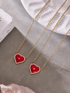 Détail du collier pendentif coeur doré avec émail rouge et bordure en zircon blanc