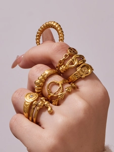 Macro shot of gold-plated geometric rings stacked on hand against purple backdrop