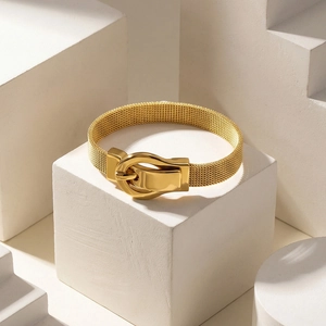 Elegant gold Milanese mesh bracelet with horseshoe buckle on minimalist stone pedestal