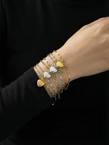 Set of gold and silver heart bracelets styled on a wrist against a dark background