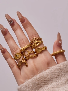 Detail of stacked gold stainless steel rings featuring hollow geometric and braided patterns