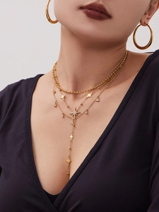 Detailansicht mehrlagiger Goldketten mit Sternanhängern und Creolen an einem Model