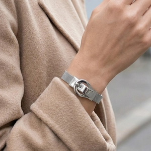 Silver woven mesh bracelet with belt buckle clasp worn with a stylish wool coat