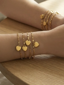 Close-up of gold heart charm bracelets featuring polished finish and layered chain details