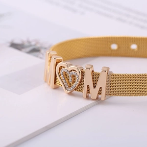 Macro shot of gold mesh strap bracelet with MOM lettering and sparkling heart charm