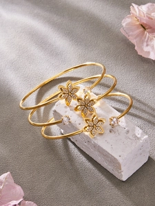 Dettaglio bracciale a fiori dorati con zirconi su pietra bianca e petali rosa