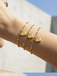 Detailed close-up of three layered gold heart bracelets with polished mirror finish