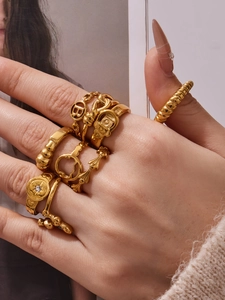 Detailed view of chunky gold rings featuring hollow B-letter, chain and buckle designs