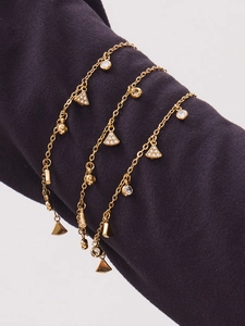 Detail von mehrlagigen Goldketten mit Zirkon-Stern und Anhängern auf violettem Ärmel