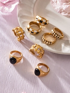 Macro view of checkered enamel rings and gold rings with black gemstones on a white tray