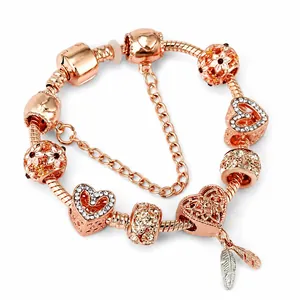 Rose gold snake chain bracelet featuring sparkling heart and feather charm pendants