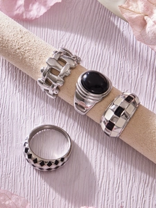 Macro shot of silver textured rings with black enamel checkered and gemstone detail