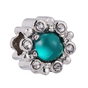 Macro shot of silver flower charm with green center stone and sparkling zircons