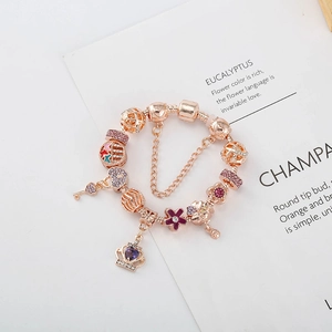 Détail du bracelet en or rose avec charms couronne violette et pendentifs en cœur