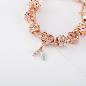 Roségold Armband mit Herz-Anhängern, Feder-Detail und funkelnden Perlen auf Schlangenkette