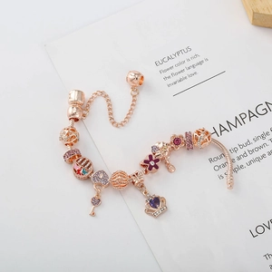 Détail du bracelet or rose avec pendentifs couronne violette, cœur et clé