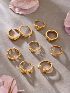 Flat lay of an 8-piece set of minimalist gold geometric rings with floral accents