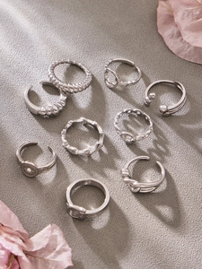 Flat lay of 9 silver minimalist rings set featuring geometric hollow and engraved designs