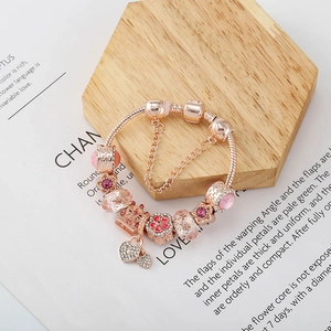 Roségoldenes Charm-Armband mit rosa Kristallen und Herzanhänger auf dekorativem Display