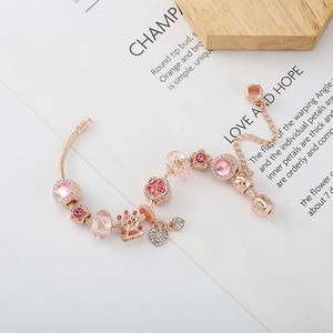 Roségoldenes Charm-Armband mit rosa Herzanhängern und Riesenrad-Perlen auf weißem Hintergrund
