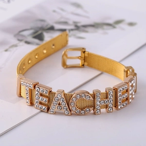 Detail of a golden mesh bracelet featuring a sparkling rhinestone TEACHER letter design