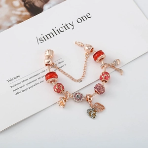 Bracelet à breloques en or rose avec perles en émail rouge et pendentifs pomme de pin