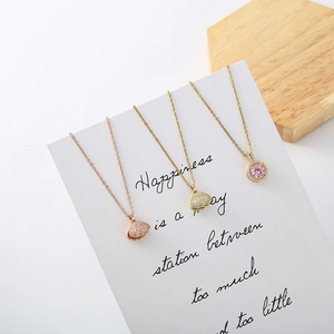 Close-up of zircon shell pendants and pink stone necklaces on elegant white card display