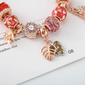 Bracelet en or rose avec cœur en émail rouge, cristaux floraux et pampilles feuilles