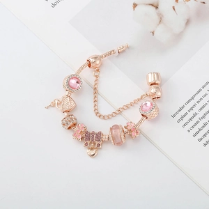 Détail d'un bracelet à breloques en or rose avec cristaux roses et pendentif Love