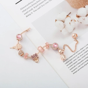 Détail d'un bracelet rose doré avec cristaux roses, pendentifs coeur et noeud