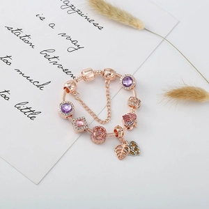 Bracelet maille serpent rose doré avec cristaux violets et pendentifs feuilles sur fond blanc